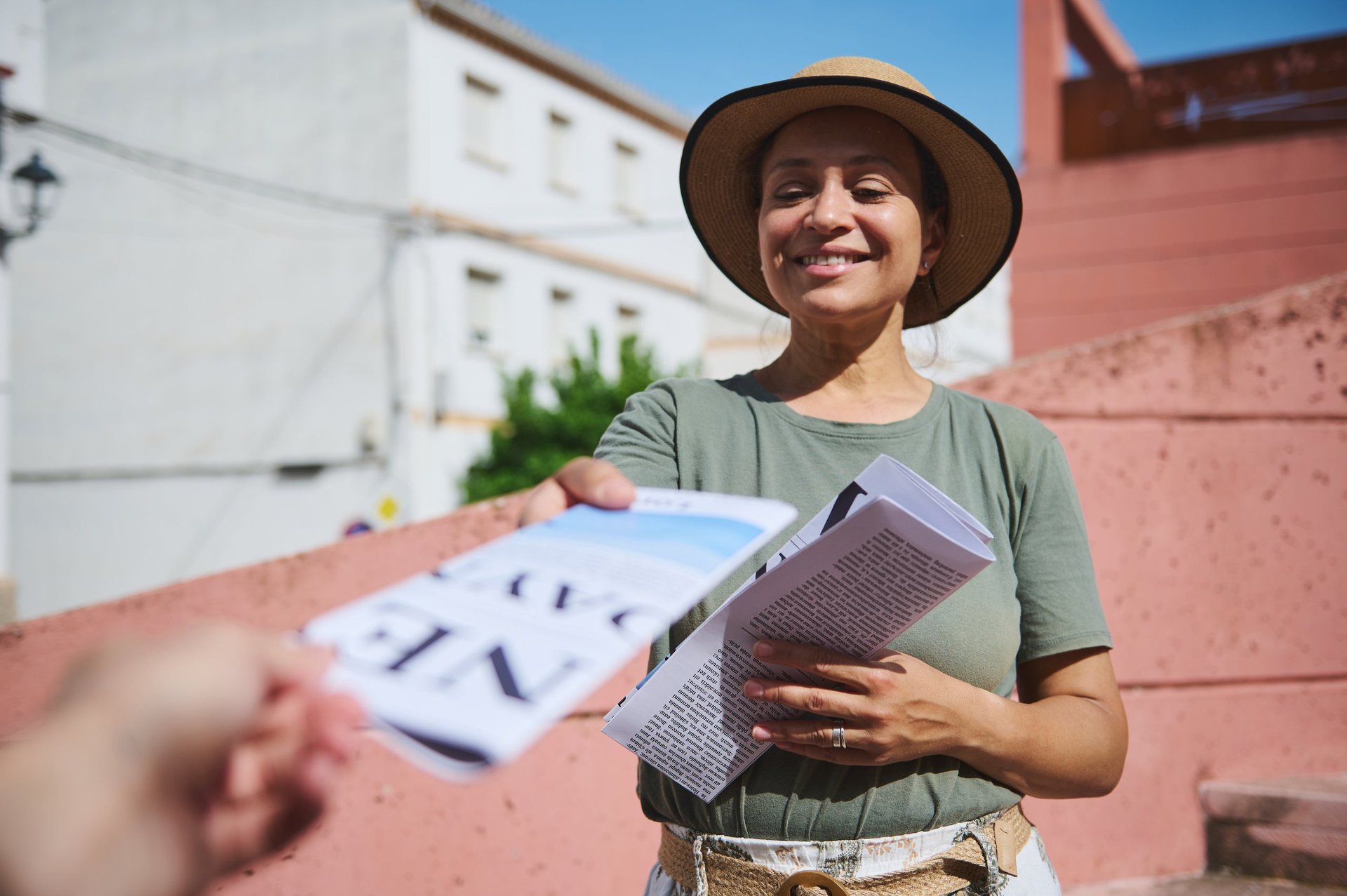 Woman handing out flyers outdoors in sunny urban setting